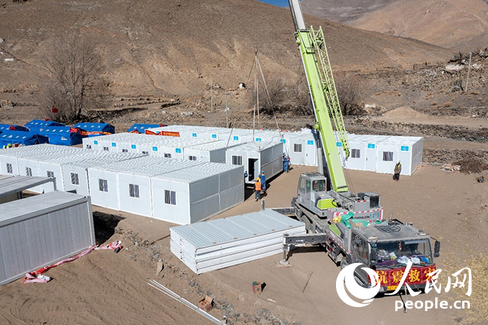 1月9日，在日喀則市定日縣長所鄉(xiāng)古榮村安置點，救援人員和施工人員合力抓緊搭建移動板房，確保受災群眾溫暖過冬。人民網(wǎng)記者 翁奇羽攝